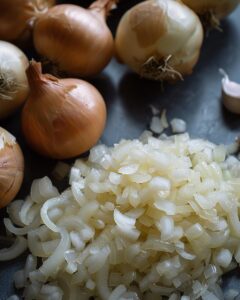 "Chef demonstrating substitute for leeks in recipe with alternative ingredients on kitchen counter."